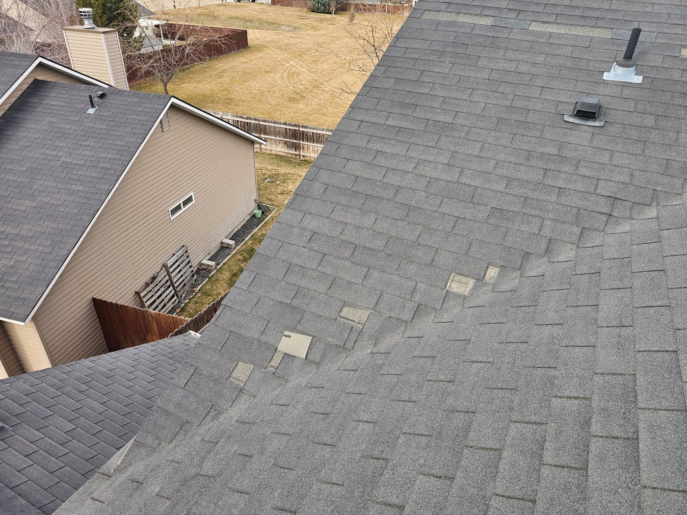 Wind-damaged shingle roof with missing tabs, documented for an insurance claim