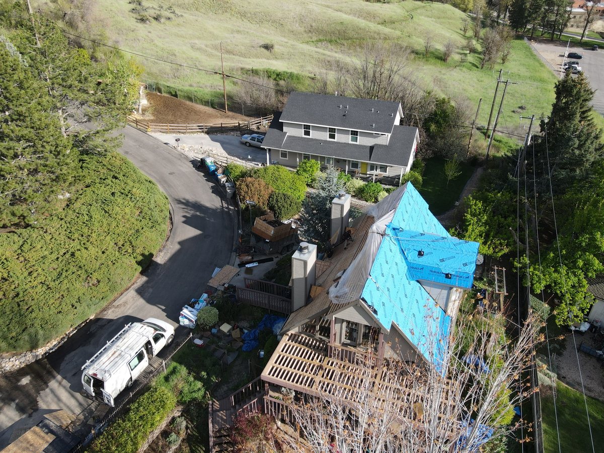 Roof mid tear-off with synthetic underlayment partially installed and the work area protected