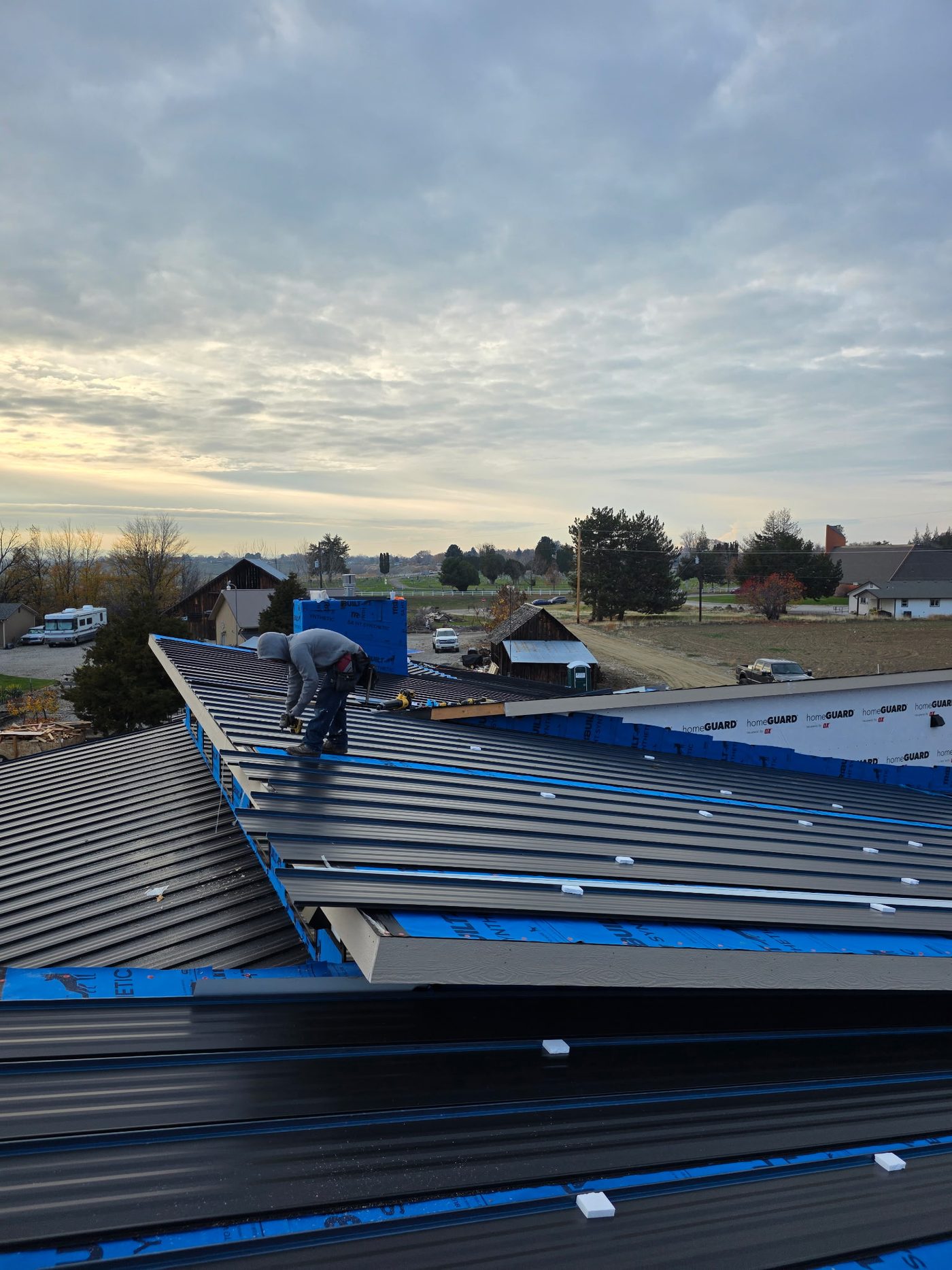 Tru Armor crew fastening standing seam metal panels at the ridge