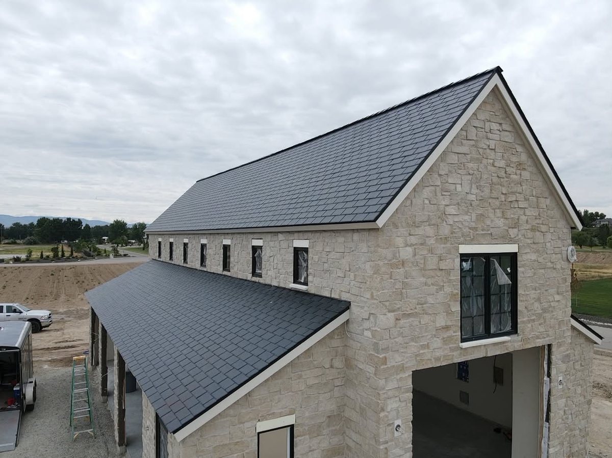 Completed synthetic slate roof installation on a stone home, photographed from roof level
